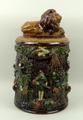 A German Majolica terracotta tobacco jar and cover, by Ahaus, the cover bearing a recumbent lion, th... 