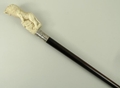 An ebony walking stick, early 20th century, the antler handle carved with a lion perched on a rock, ... 