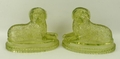 A pair of 19th century pressed green glass figures of recumbent dogs lying on oval fluted bases, pro... 