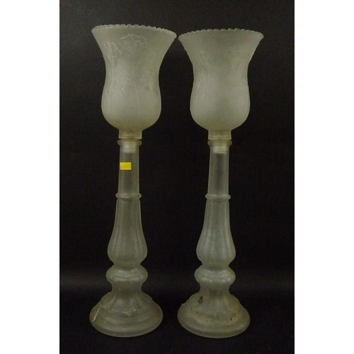 23 - A pair of frosted glass candlesticks, with bell shaped shades decorated with low relief floral motif... 