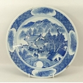 An 18th century, Chinese plate, decorated in underglaze blue with a village scene, the rim with rese... 