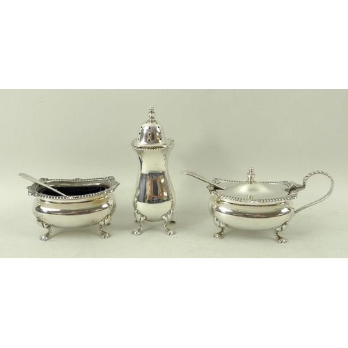 371 - A silver three piece cruet set, comprising salt and mustard with blue glass liners and spoons, and p... 