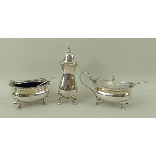 371 - A silver three piece cruet set, comprising salt and mustard with blue glass liners and spoons, and p... 