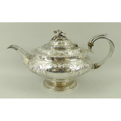 406 - A Georgian silver teapot, the squat embossed floral body with applied cast rim and foliate border, w... 