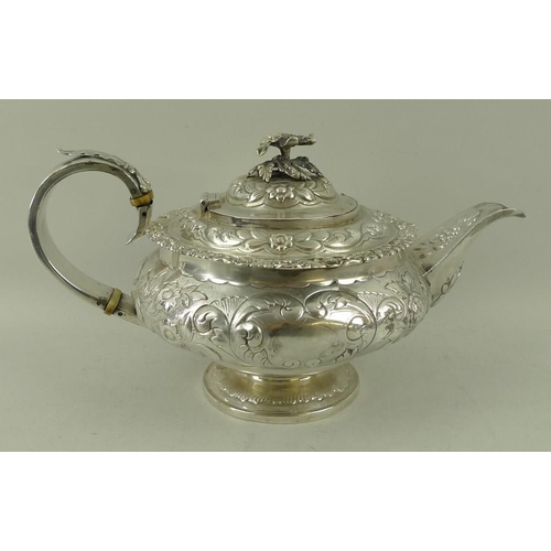 406 - A Georgian silver teapot, the squat embossed floral body with applied cast rim and foliate border, w... 