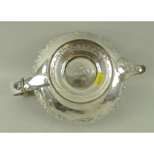 406 - A Georgian silver teapot, the squat embossed floral body with applied cast rim and foliate border, w... 