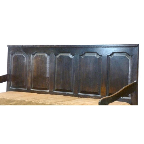 658 - A 18th century oak long settle, with five fielded panel back rest, shaped open arms, raised on cabri... 