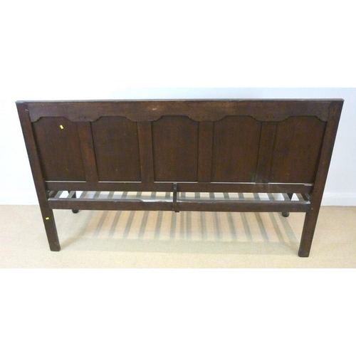 658 - A 18th century oak long settle, with five fielded panel back rest, shaped open arms, raised on cabri... 