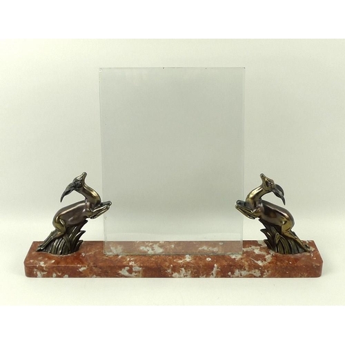 713 - An Art Deco freestanding photograph frame, the red marble plinth with two bronzed leaping springbok ... 