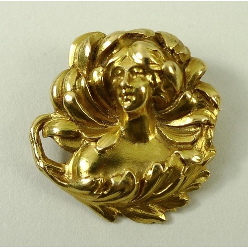 773 - An Art Nouveau yellow metal brooch of circular design with naturalistic swirling adornments to a fem... 