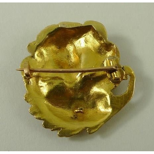 773 - An Art Nouveau yellow metal brooch of circular design with naturalistic swirling adornments to a fem... 