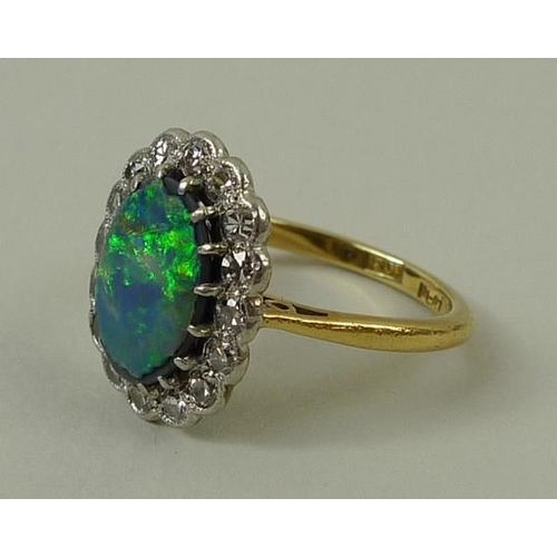 781 - An 18ct gold, opal and diamond ring, the central oval cut opal set in platinum and surrounded by six... 