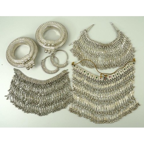 792A - A collection of Arabic white metal Bedouin jewellery, comprising a pair of hoop earrings, two bangle... 