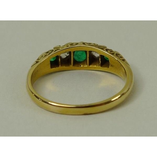 809 - An emerald and diamond five stone ring with three emeralds, interspersed with two diamonds within sc... 