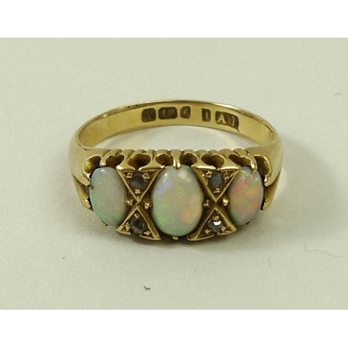 811 - An 18ct gold, opal and diamond ring, the three graduated oval cut opals divided by two pairs of chip... 