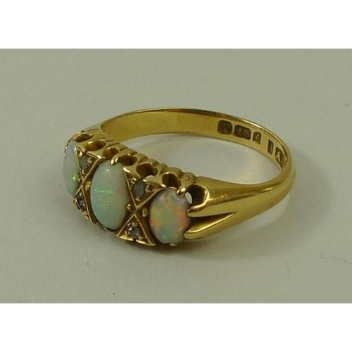 811 - An 18ct gold, opal and diamond ring, the three graduated oval cut opals divided by two pairs of chip... 