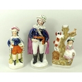 A group of three Staffordshire figures, late 19th century, comprising a man dressed in a cape, hat, ... 