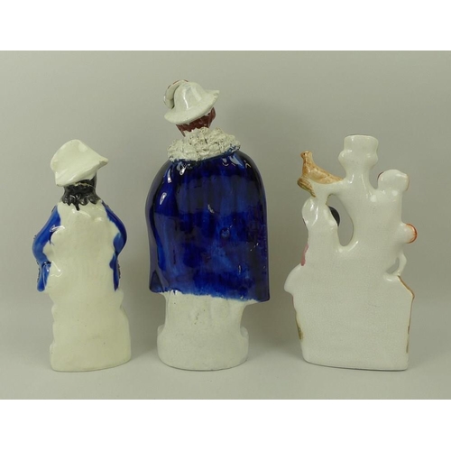 520 - A group of three Staffordshire figures, late 19th century, comprising a man dressed in a cape, hat, ... 