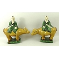 A pair of earthenware Tang style figurines, each depicting a Buddhist figure riding an ox, in green ... 