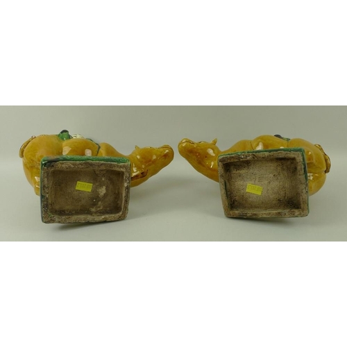 526 - A pair of earthenware Tang style figurines, each depicting a Buddhist figure riding an ox, in green ... 