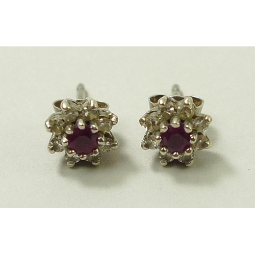 801 - A pair of ear studs set with central ruby surrounded by eight diamonds in a flower setting.