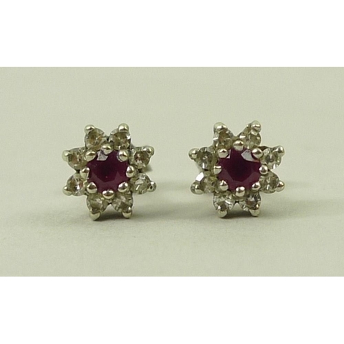 801 - A pair of ear studs set with central ruby surrounded by eight diamonds in a flower setting.