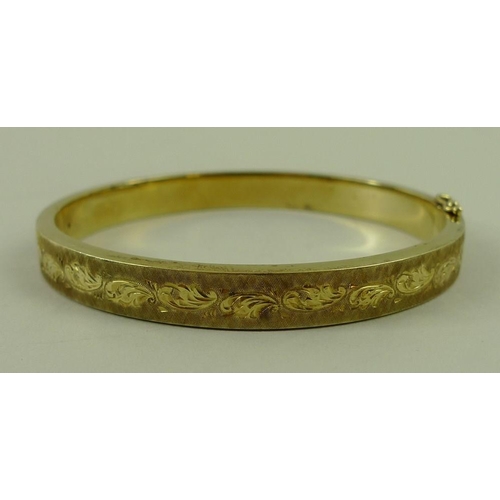 802 - A 14ct gold bangle, with engraved and textured decoration, 15.8g.