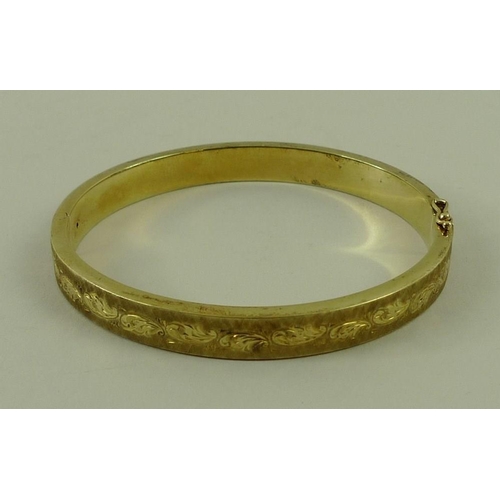 802 - A 14ct gold bangle, with engraved and textured decoration, 15.8g.