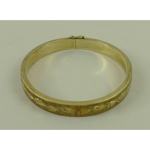 802 - A 14ct gold bangle, with engraved and textured decoration, 15.8g.