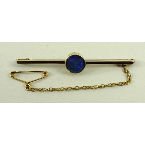 819 - A 15ct gold and black opal bar brooch, the central circular black opal in a beaded setting, 3.2g tot... 