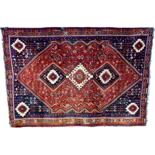 892A - A Shiraz rug with red ground, three central medallions, one cream and two dark blue, field decorated... 