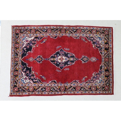 1026 - An Iranian rug with open red ground, central dark blue medallion with pendants, black and cream corn... 