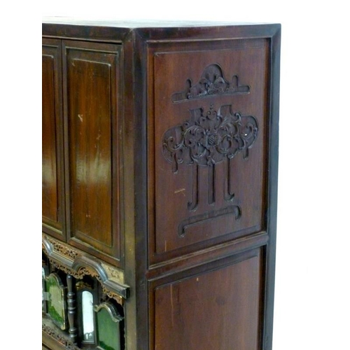 1037 - An early 20th century Chinese carved hardwood cabinet, with two panel doors over a set of four reces... 