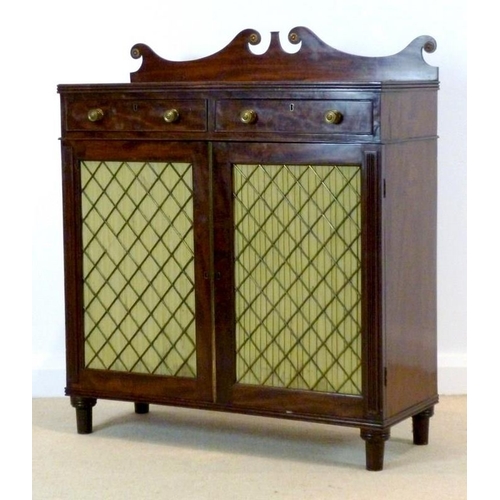 1047 - A Regency mahogany press cupboard, the scroll shaped gallery with brass paterae mounts, over two fri... 