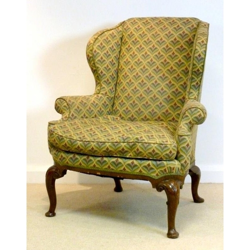 1050 - A George I style walnut framed wing back armchair, circa 1900, with scroll over arms, upholstered in... 