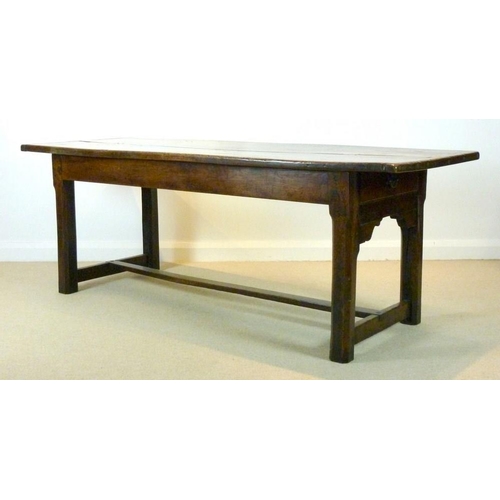 1056 - An early 18th century oak refectory table, the cleated twin plank top above a drawer to one end on s... 