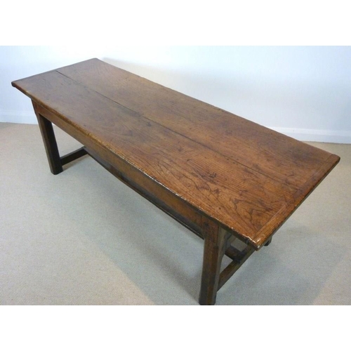 1056 - An early 18th century oak refectory table, the cleated twin plank top above a drawer to one end on s... 