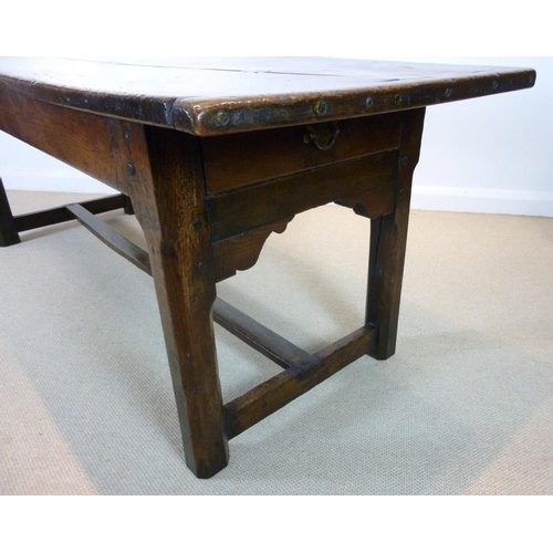 1056 - An early 18th century oak refectory table, the cleated twin plank top above a drawer to one end on s... 