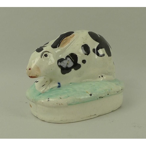 532 - A Staffordshire model of a rabbit, 19th century, on oval base, hand painted black and white, 8cm lon... 