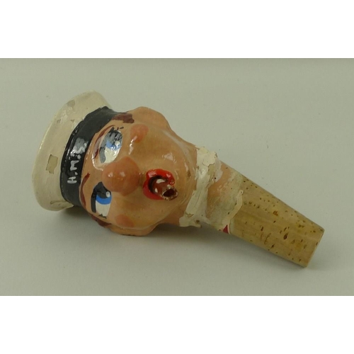 708 - A 1930's papier mache bottle stop of a H.M.S sailor with cigar, on a cork stopper, 12cm.