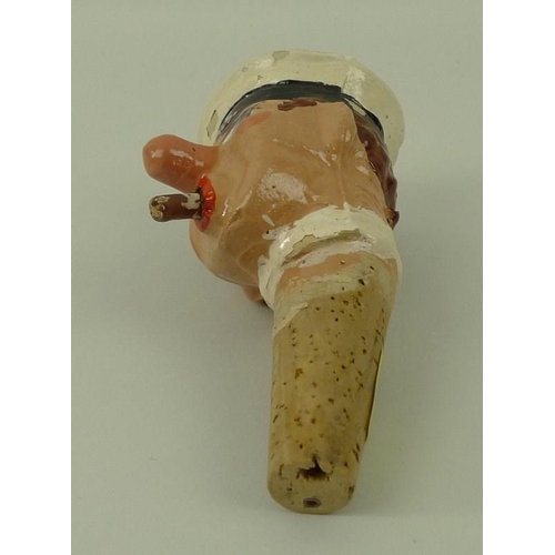 708 - A 1930's papier mache bottle stop of a H.M.S sailor with cigar, on a cork stopper, 12cm.