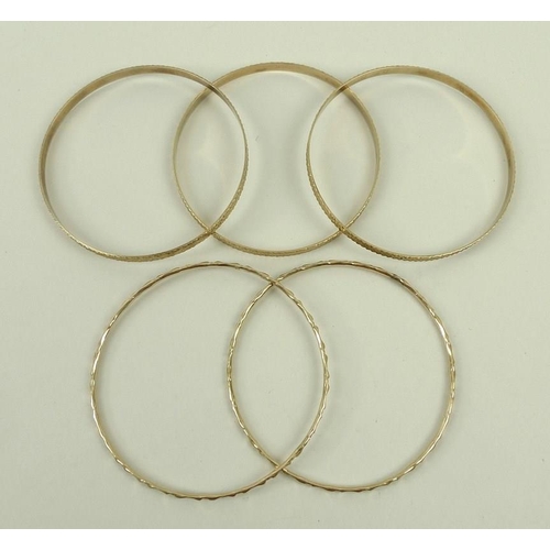 829 - A group of three 9ct gold bangles, and a pair of bangles, 29.1g total weight. (5)