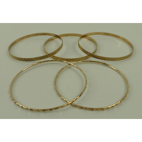 829 - A group of three 9ct gold bangles, and a pair of bangles, 29.1g total weight. (5)