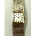 A lady's 9ct gold Omega wristwatch, the square pearlised face with baton numerals, on a woven gold m... 