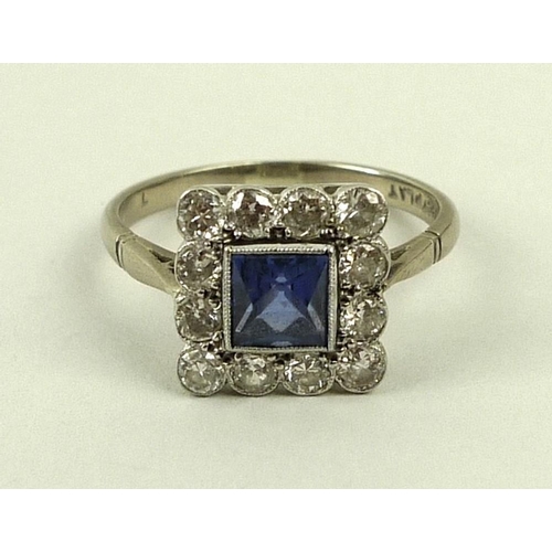 849 - An 18ct white gold, sapphire and diamond ring, circa 1900, the central square cut sapphire surrounde... 