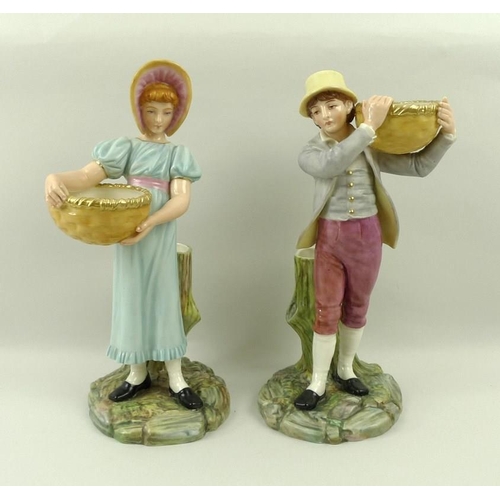 520 - A pair of Royal Worcester blush ivory porcelain figurines, modelled as a boy and girl each carrying ... 