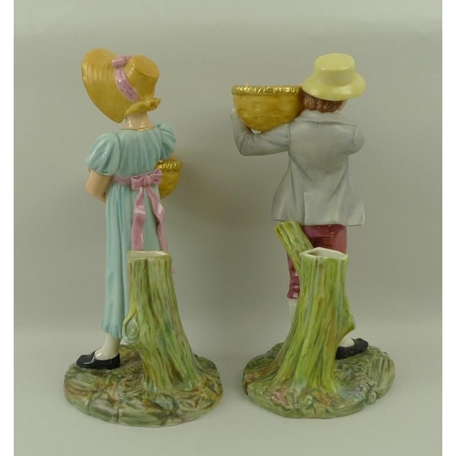 520 - A pair of Royal Worcester blush ivory porcelain figurines, modelled as a boy and girl each carrying ... 