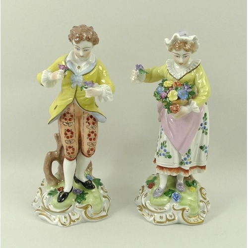 527 - A pair of Dresden figurines, depicting a male and female with flowers, on gilt highlighted scroll ba... 