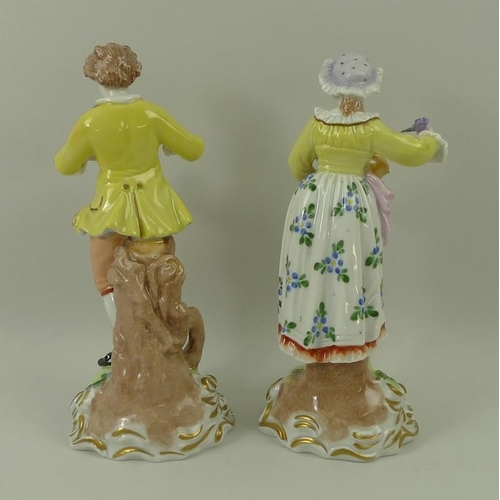 527 - A pair of Dresden figurines, depicting a male and female with flowers, on gilt highlighted scroll ba... 