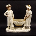 A Royal Worcester ivory porcelain figural group, of a girl and boy holding a basket, with gilded hig... 